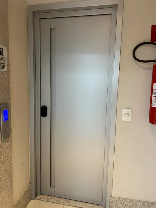 Puerta gris con tirador embutido en un hall
